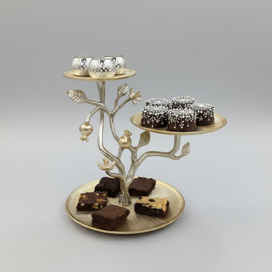 Decorative metal tree-shaped platter with small containers and brownies on a wooden table.