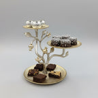 Decorative metal tree-shaped platter with small containers and brownies on a wooden table.