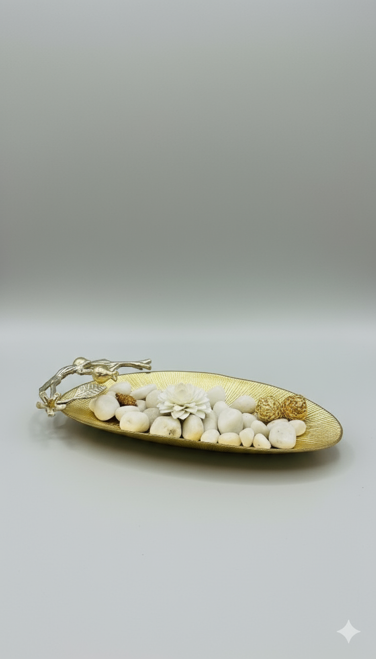Decorative tray with pebbles and dried plants on a white surface against a blue wall.